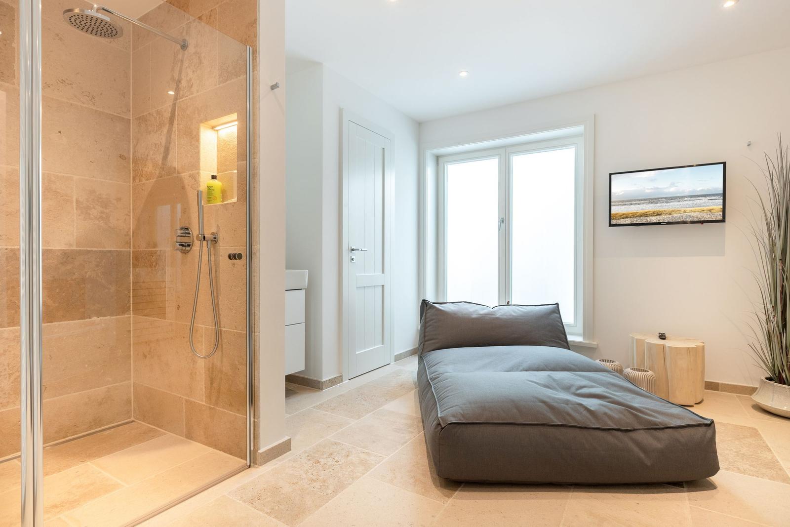 Shower area with glass enclosure, bed, and window in bedroom
