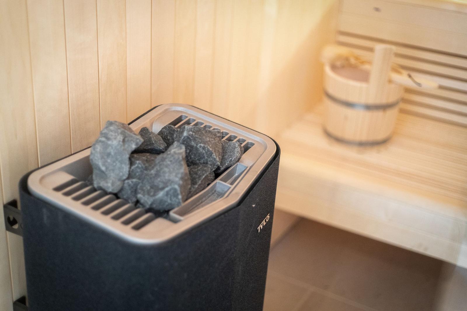 Sauna with stone heater and wooden bench in background