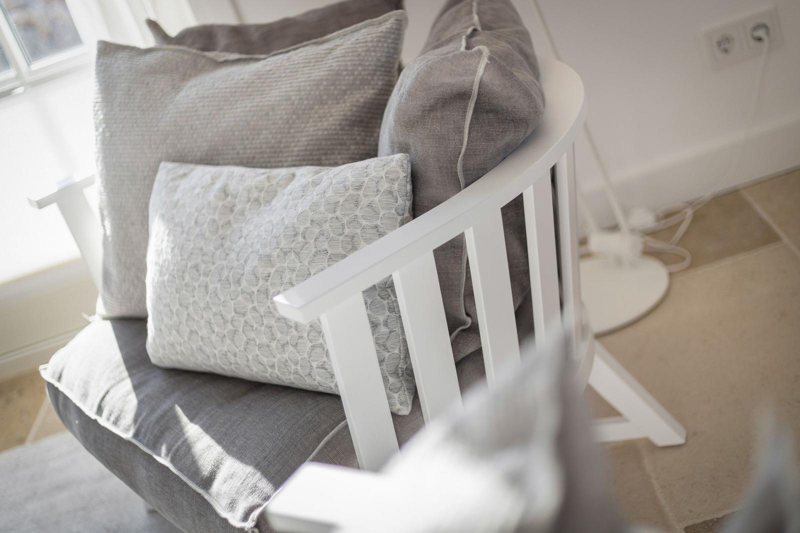 White chair with gray cushions and patterned cushions