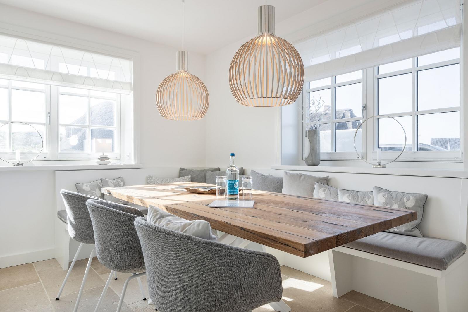 Dining room with wooden table, bench, and two pendant lamps.