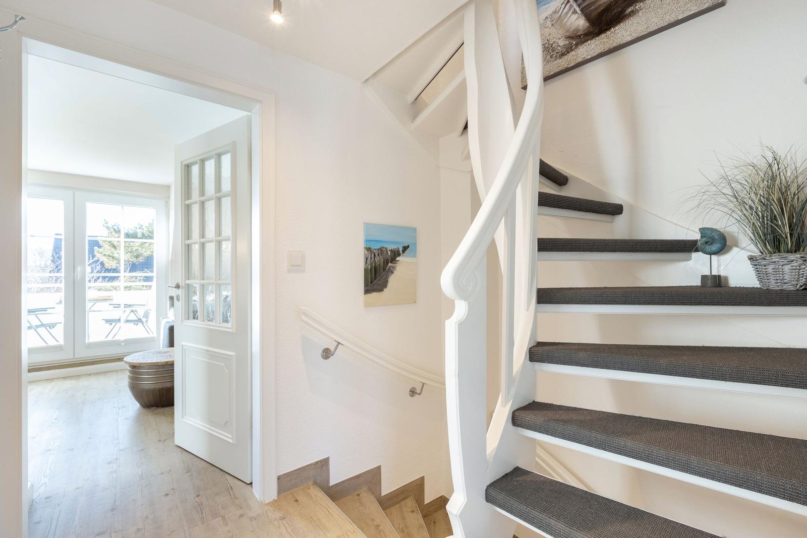 House with staircase and door to balcony. Wall art and plant are visible.
