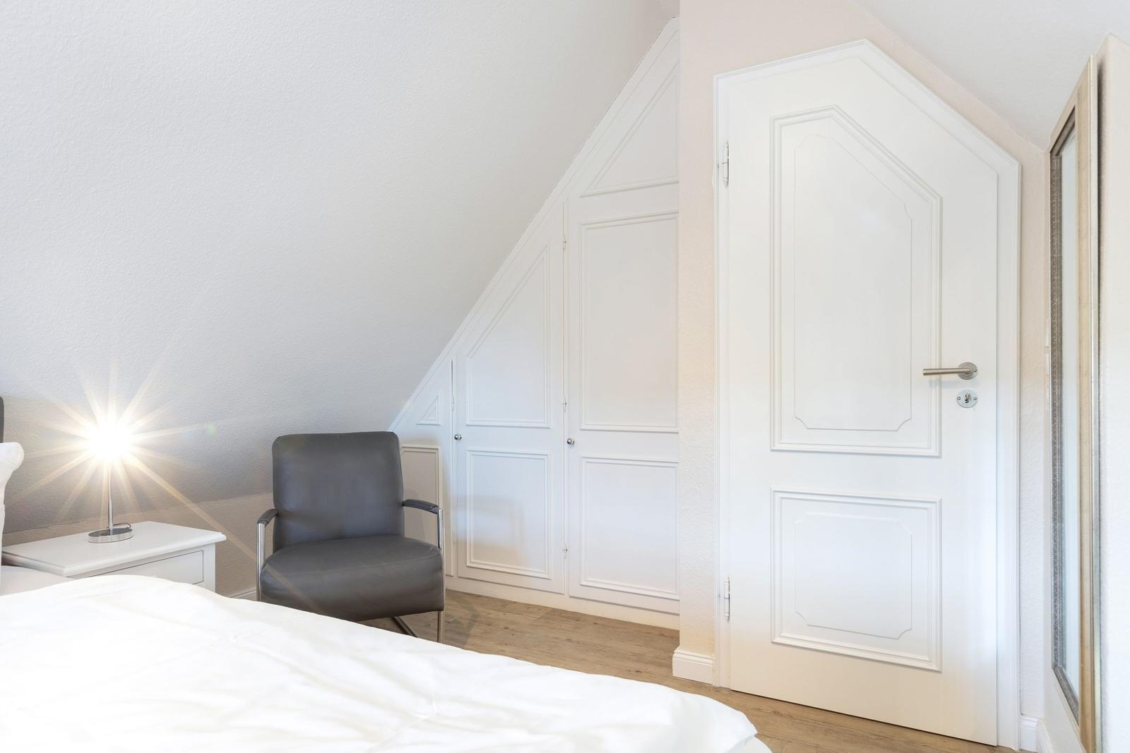 Bedroom with bed, chair, and nightstand under sloped ceiling
