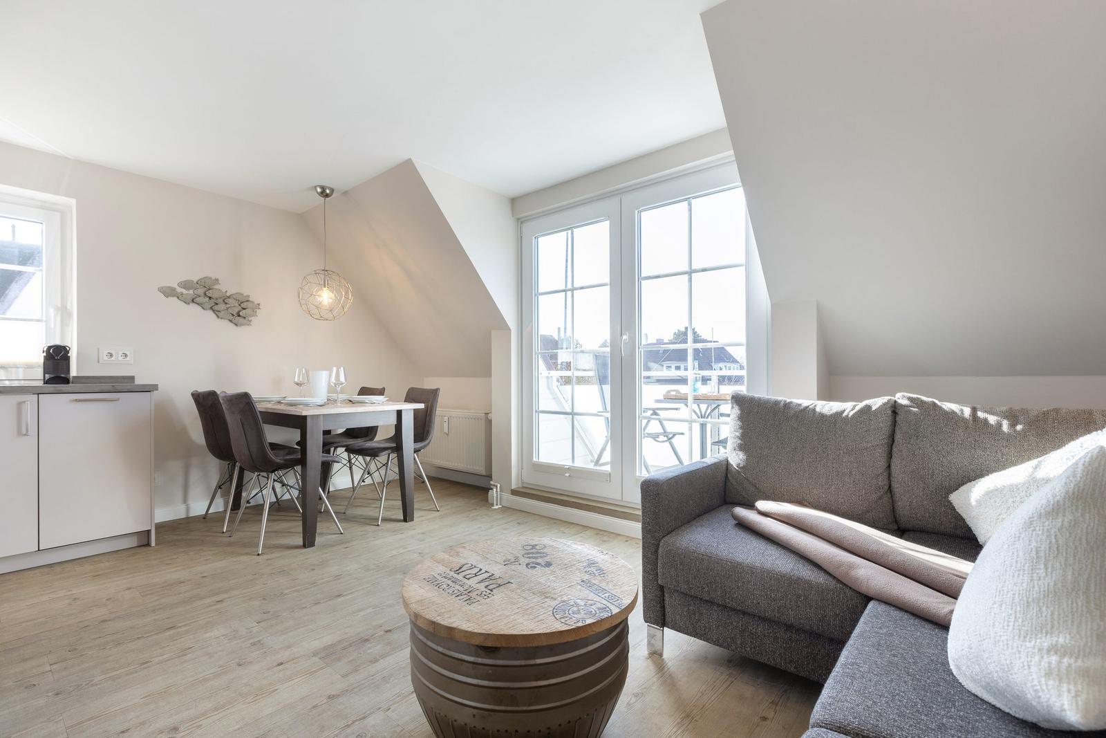 Living and dining area with sofa, table, and windows to the terrace.