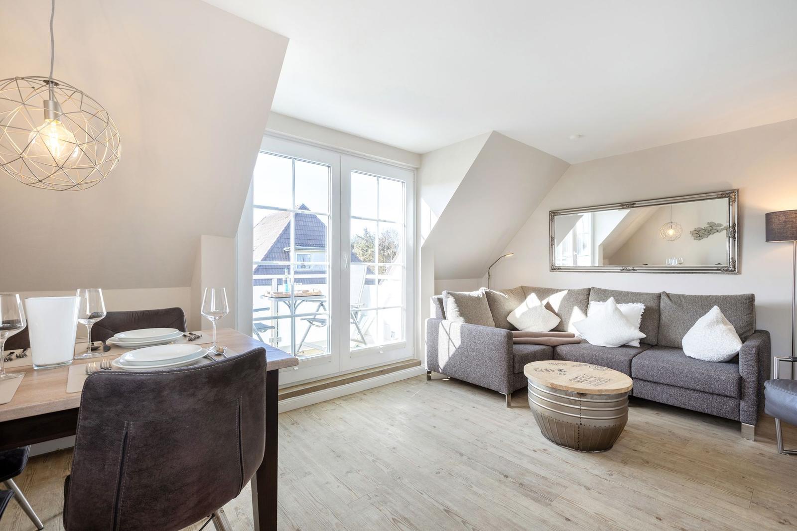 Living and dining area with sofa, table, and window to terrace.