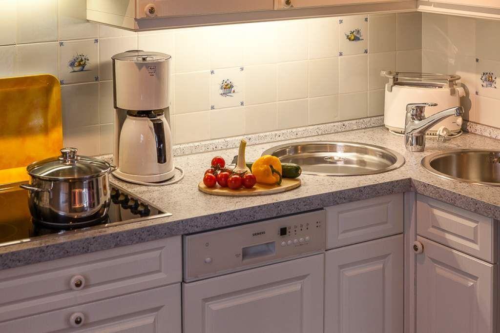 Kitchen with sink, stove, coffee maker, and fruit on countertop.
