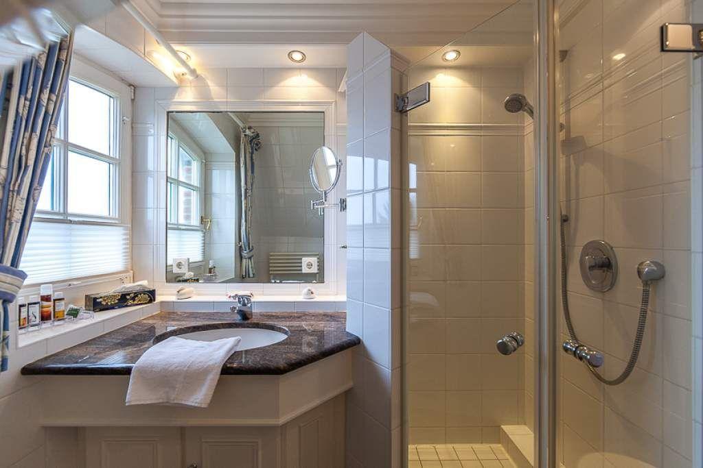 Bathroom with shower, sink, and window.