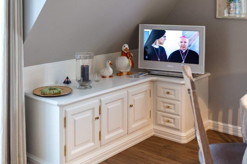 TV on white cabinet with decorative figures and candle