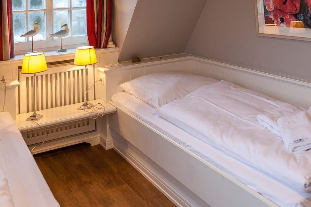 Bedroom with white bed, nightstand, and window with seagull figurines.