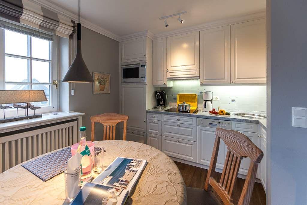Kitchen with dining area, white cabinets, and wooden chairs. Window with view outside.