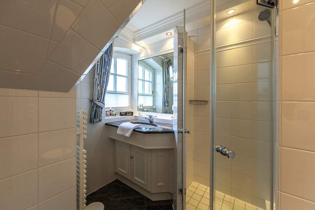 Bathroom with shower, sink, and window.