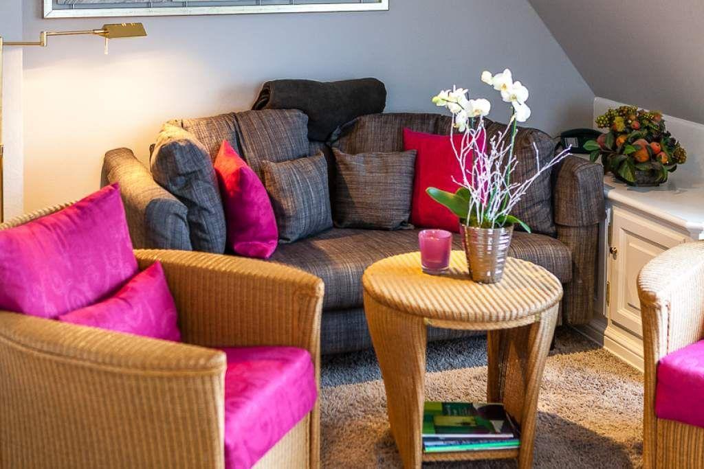 Living room with sofa, chairs, and table. Decorated with flowers and cushions.