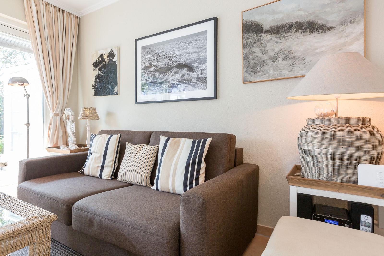 A living room with a brown sofa, cushions, and wall art.