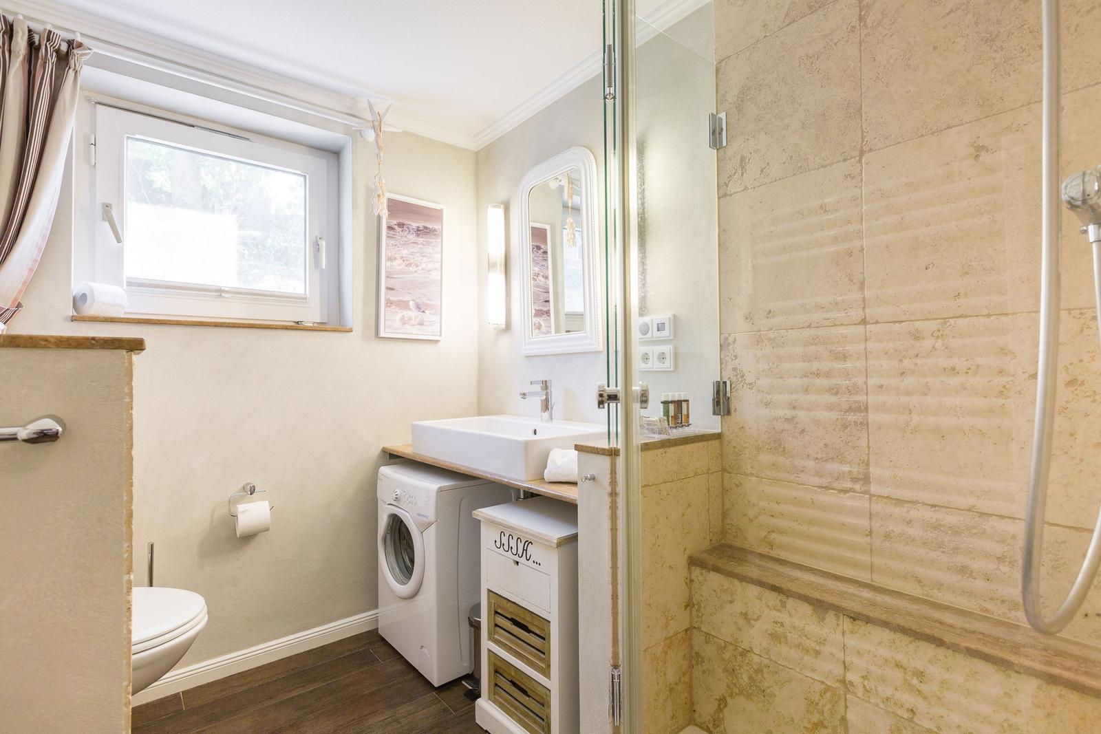 Bathroom with shower, washing machine, and window