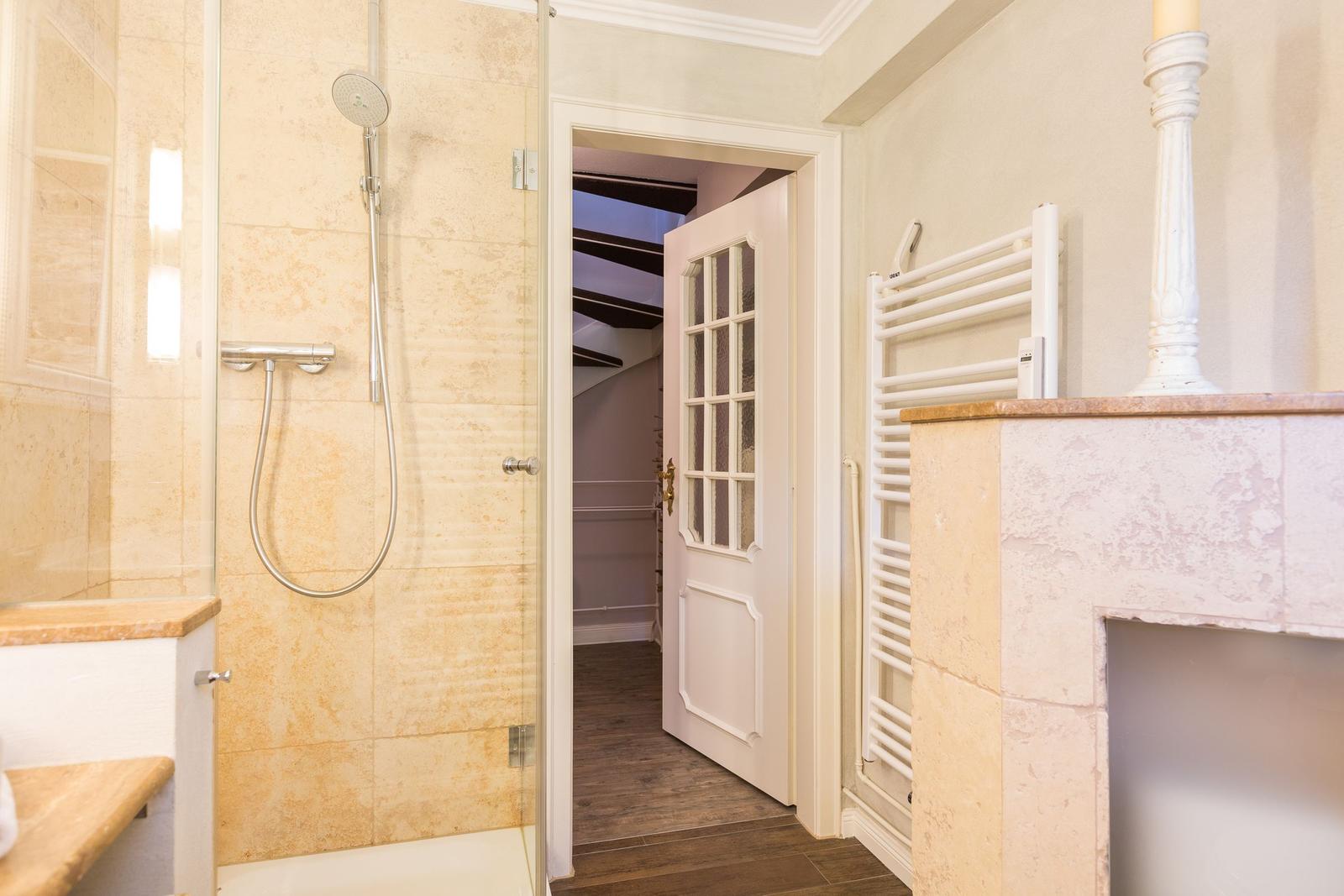 Shower with glass enclosure, door to hallway, and heater
