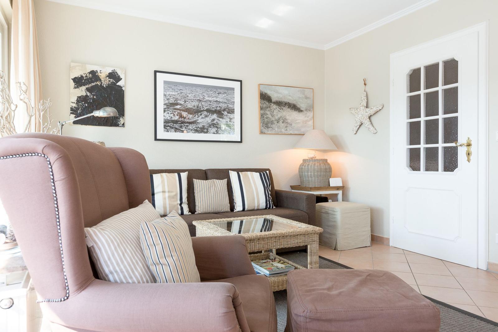 Living room with armchair, sofa, table, and wall decor.