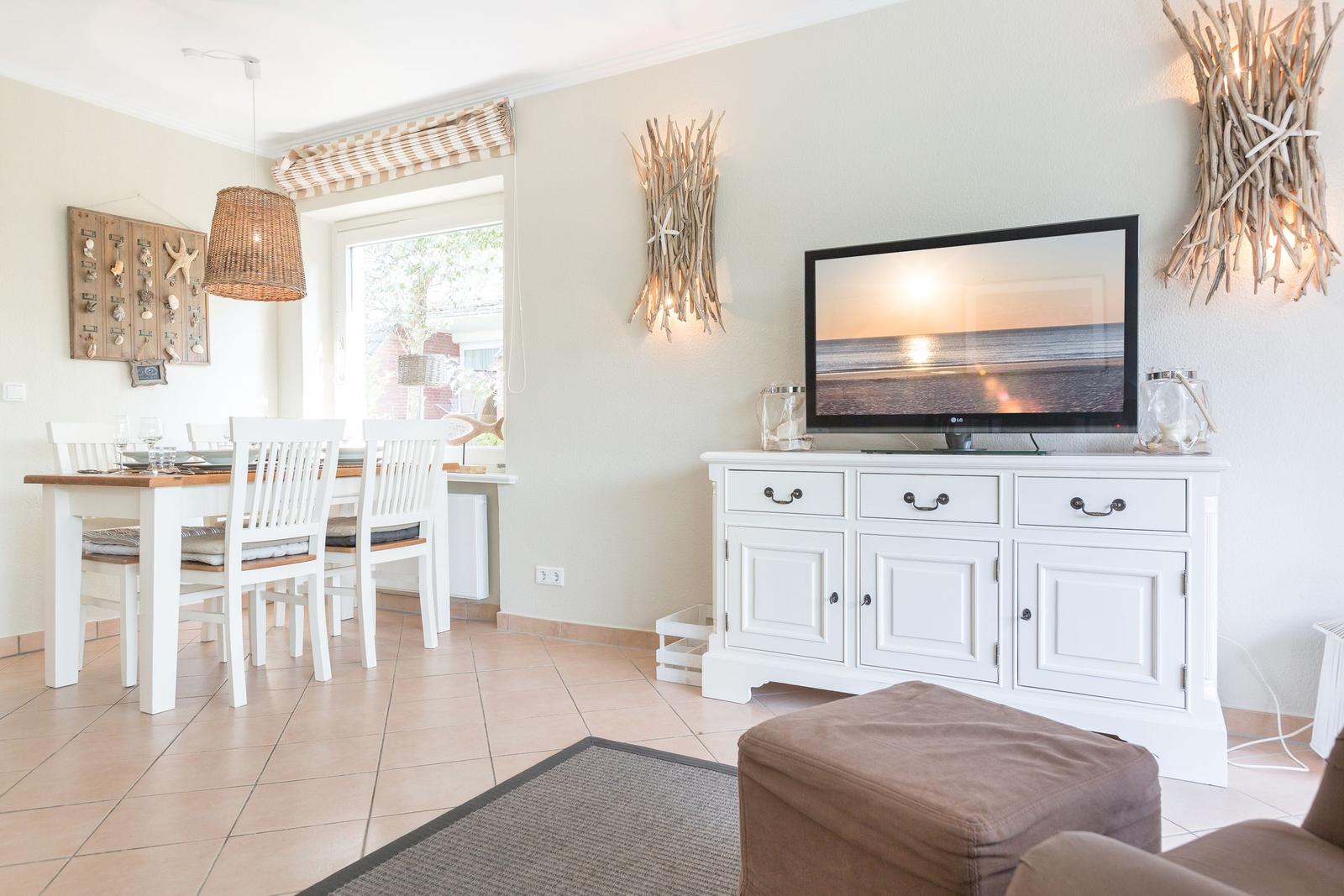 Living and dining area with TV, dining table, and beach decor.