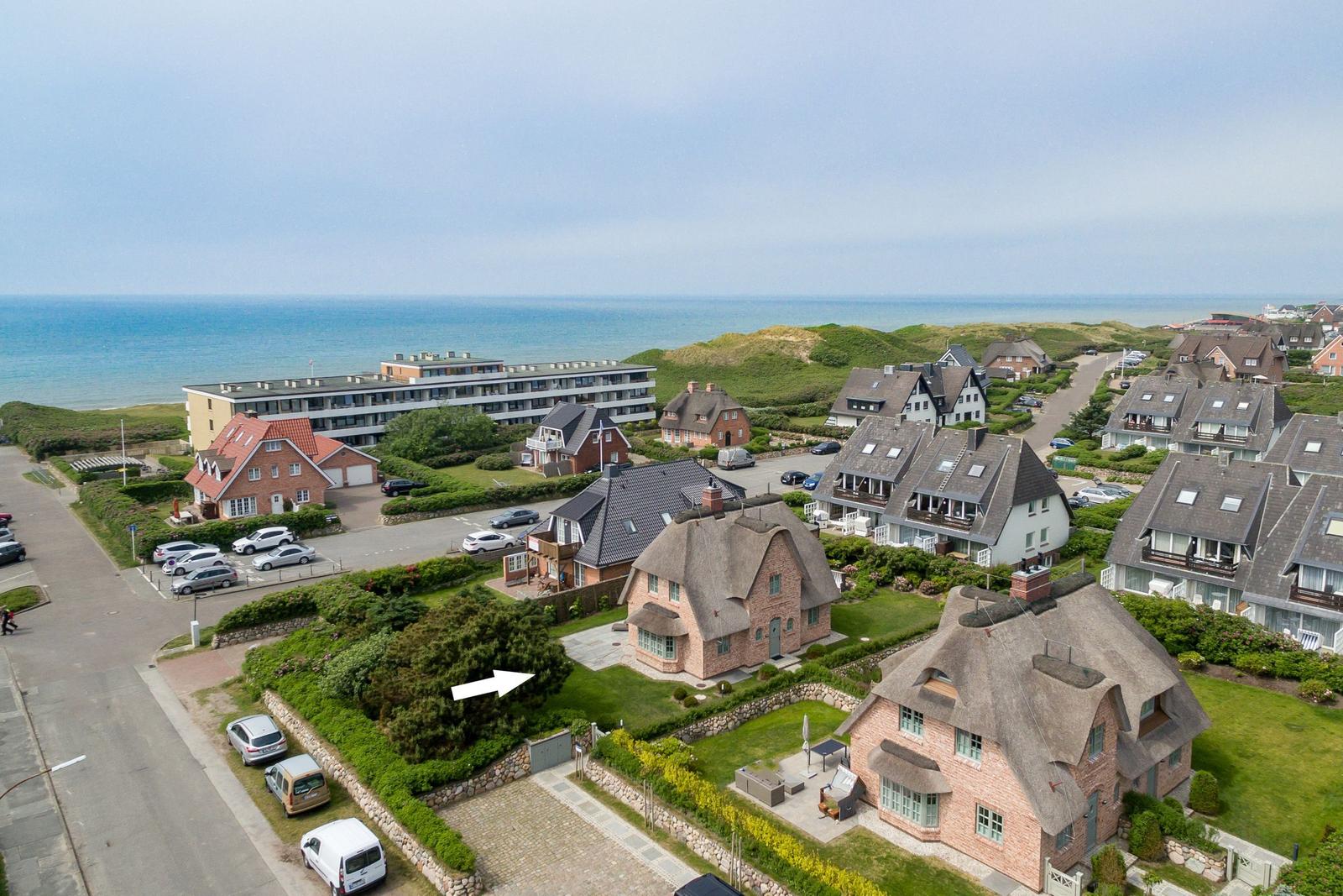 Haus mit Dach und Garten, Blick auf Meer und Strand.