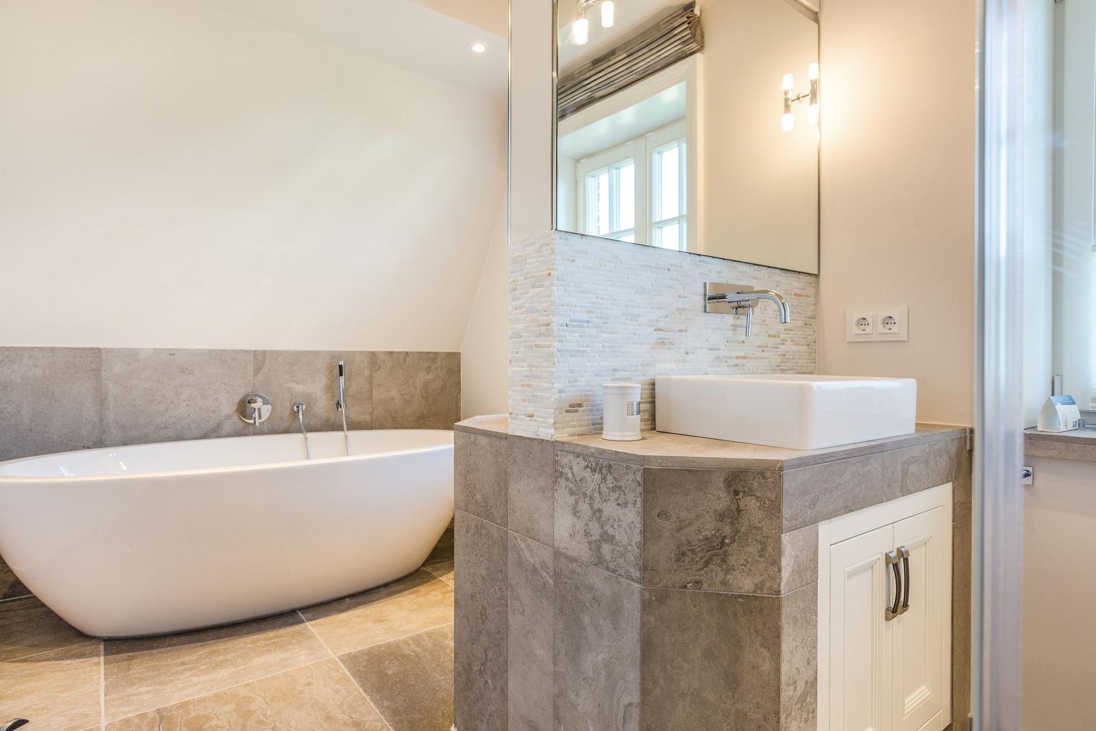 Bad mit freistehender Badewanne und Waschbecken auf Marmorunterbau.