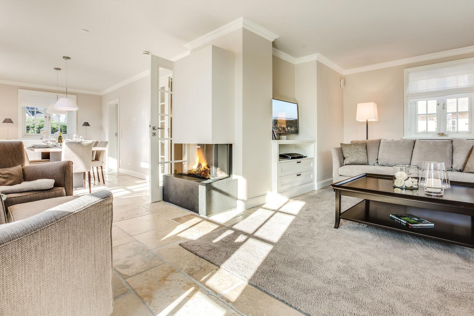 Wohnzimmer mit Kamin, Sofa und Couchtisch. Blick in die Küche.