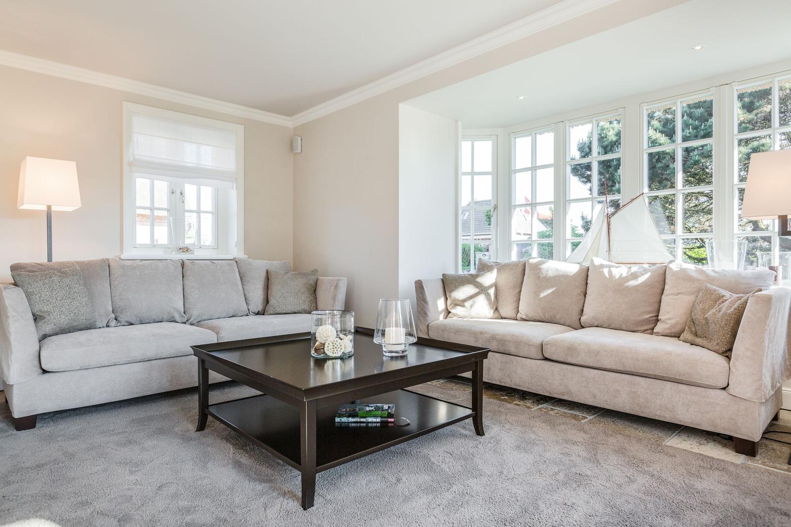 Wohnzimmer mit zwei Sofas, Couchtisch und Fenstern.
