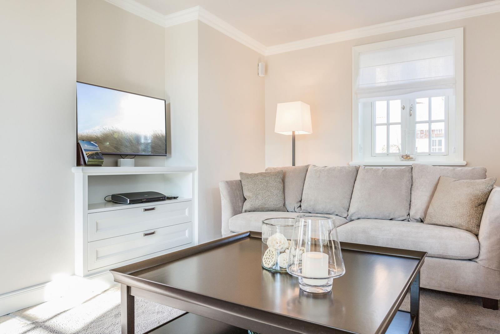 Ein Wohnzimmer mit Sofa, Fernseher und Tisch.