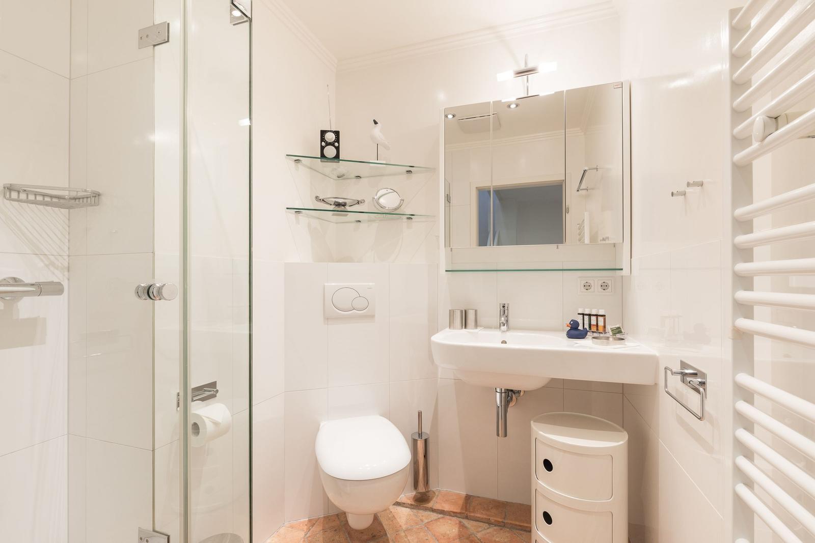 Badezimmer mit Dusche, Waschbecken und Toilette.