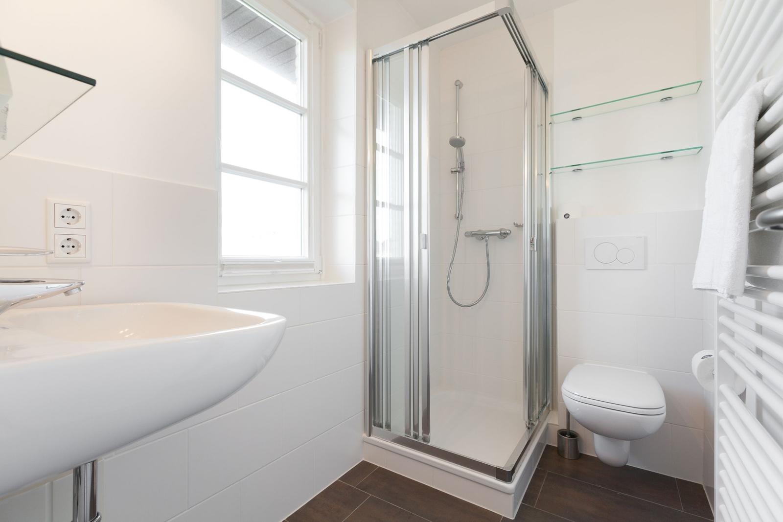Badezimmer mit Dusche, Waschbecken und Toilette.