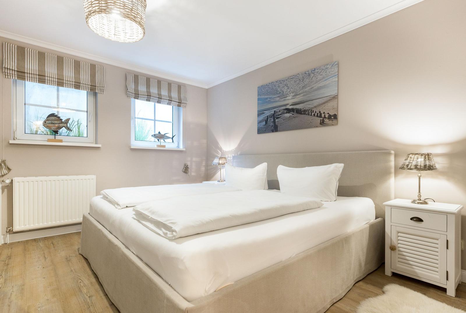 Bedroom with double bed, two windows, and wall art.