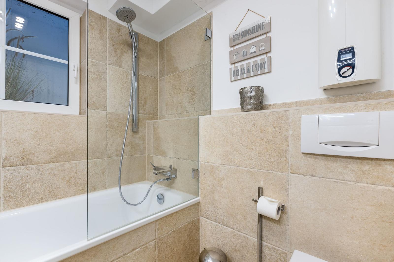 Bathroom with bathtub, shower, and window.