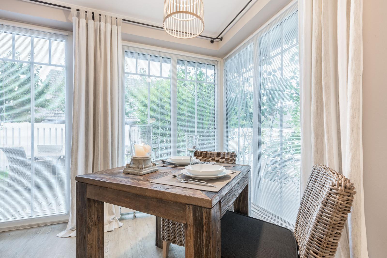 Dining room with wooden table, chairs, and windows to the garden.