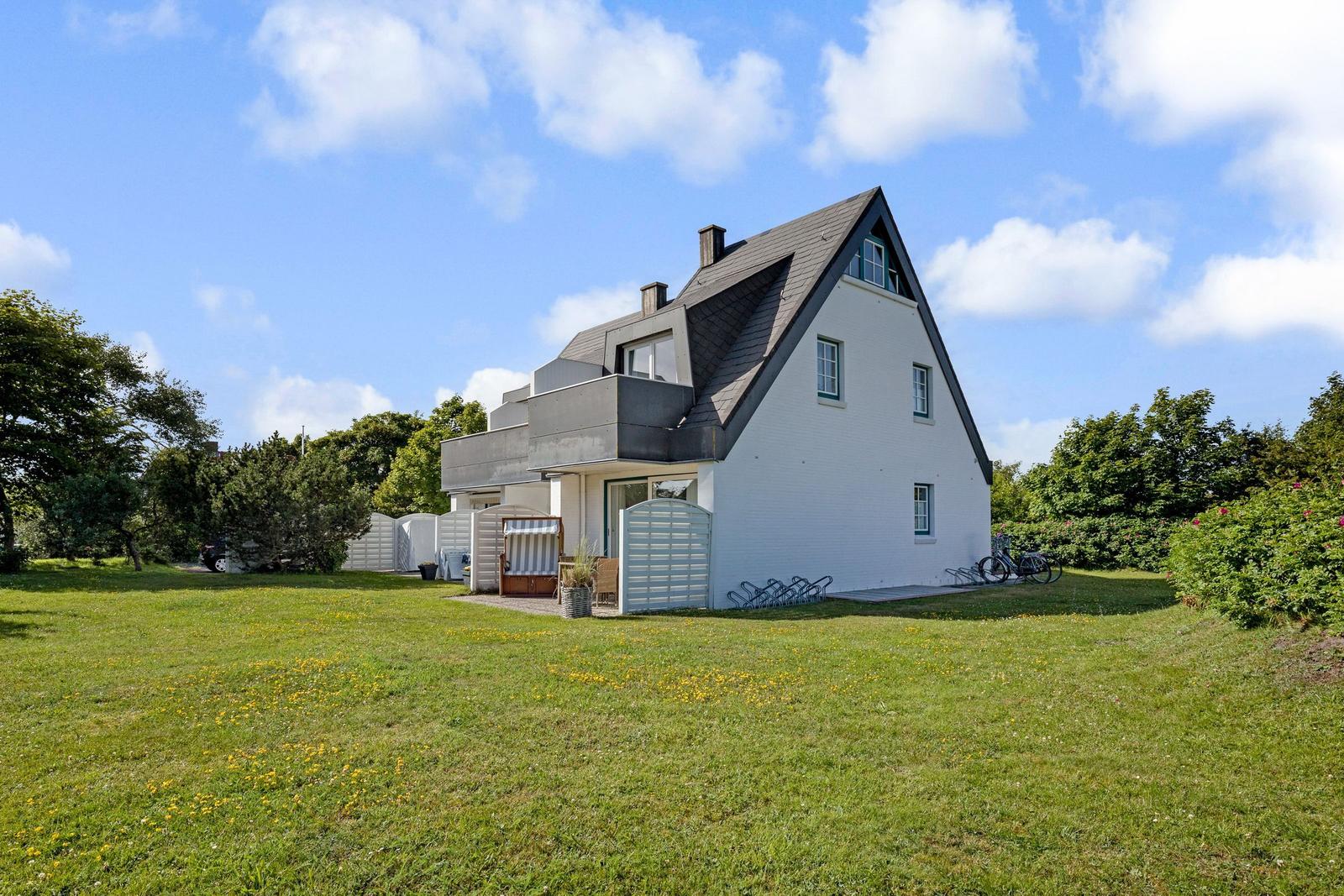 Weiße Villa mit grünem Garten und Fahrrädern
