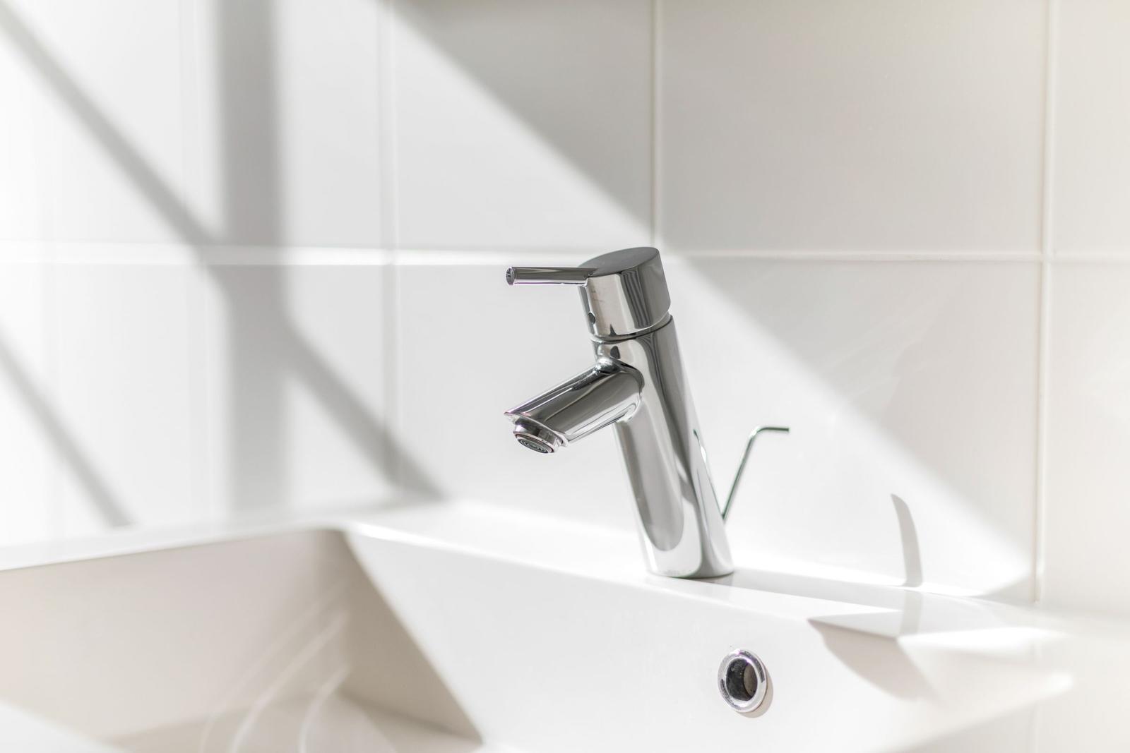 Moderne Waschbecken mit Chromarmatur und weißen Fliesen