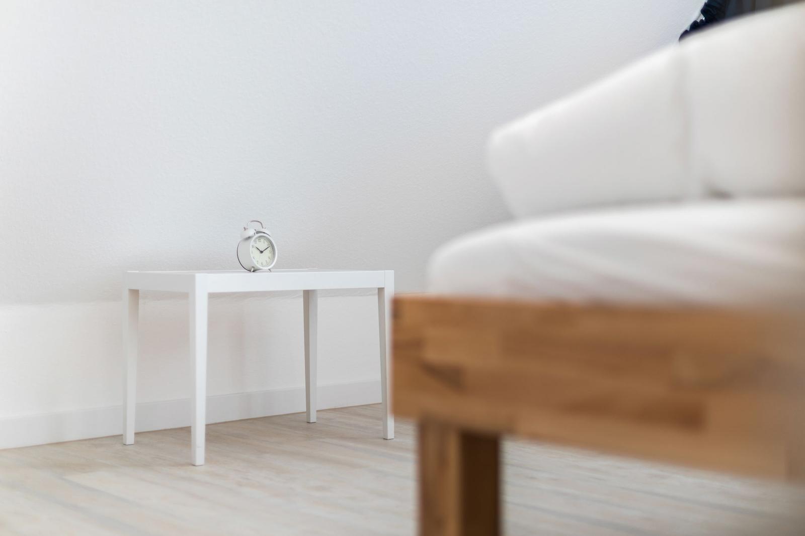 Ein weißer Tisch mit Wecker neben einem Sofa
