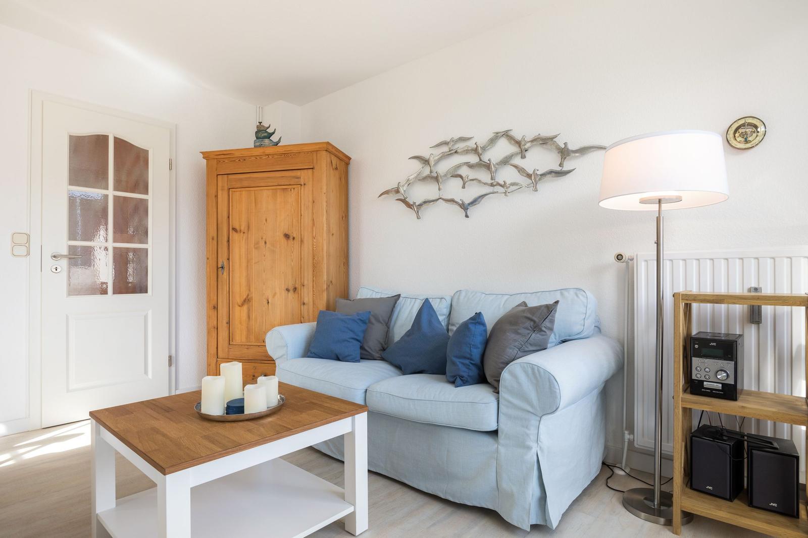 Wohnzimmer mit Sofa, Holzschrank und Stehlampe.