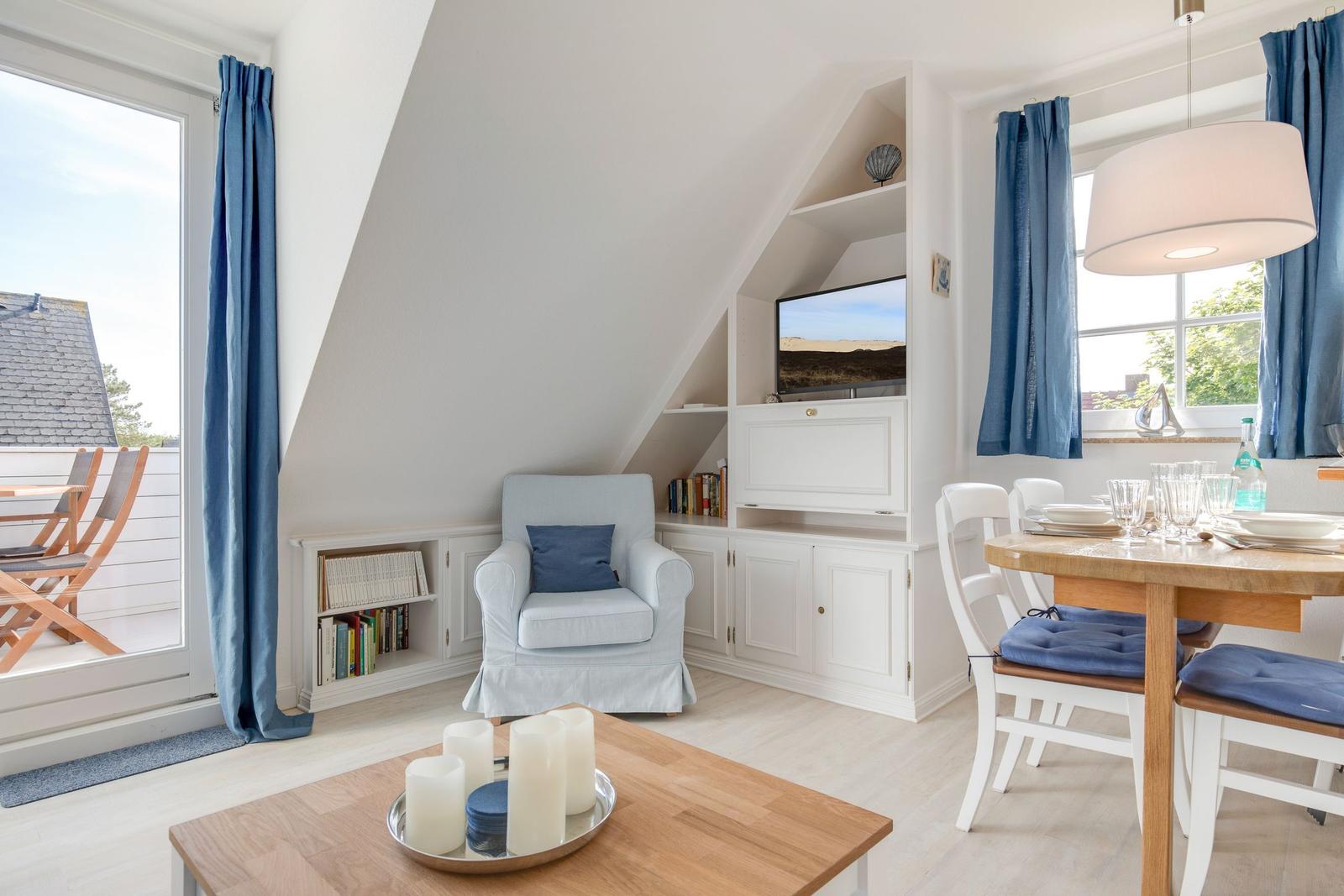 Wohn- und Essbereich mit TV, Bücherregal und Terrassentür.