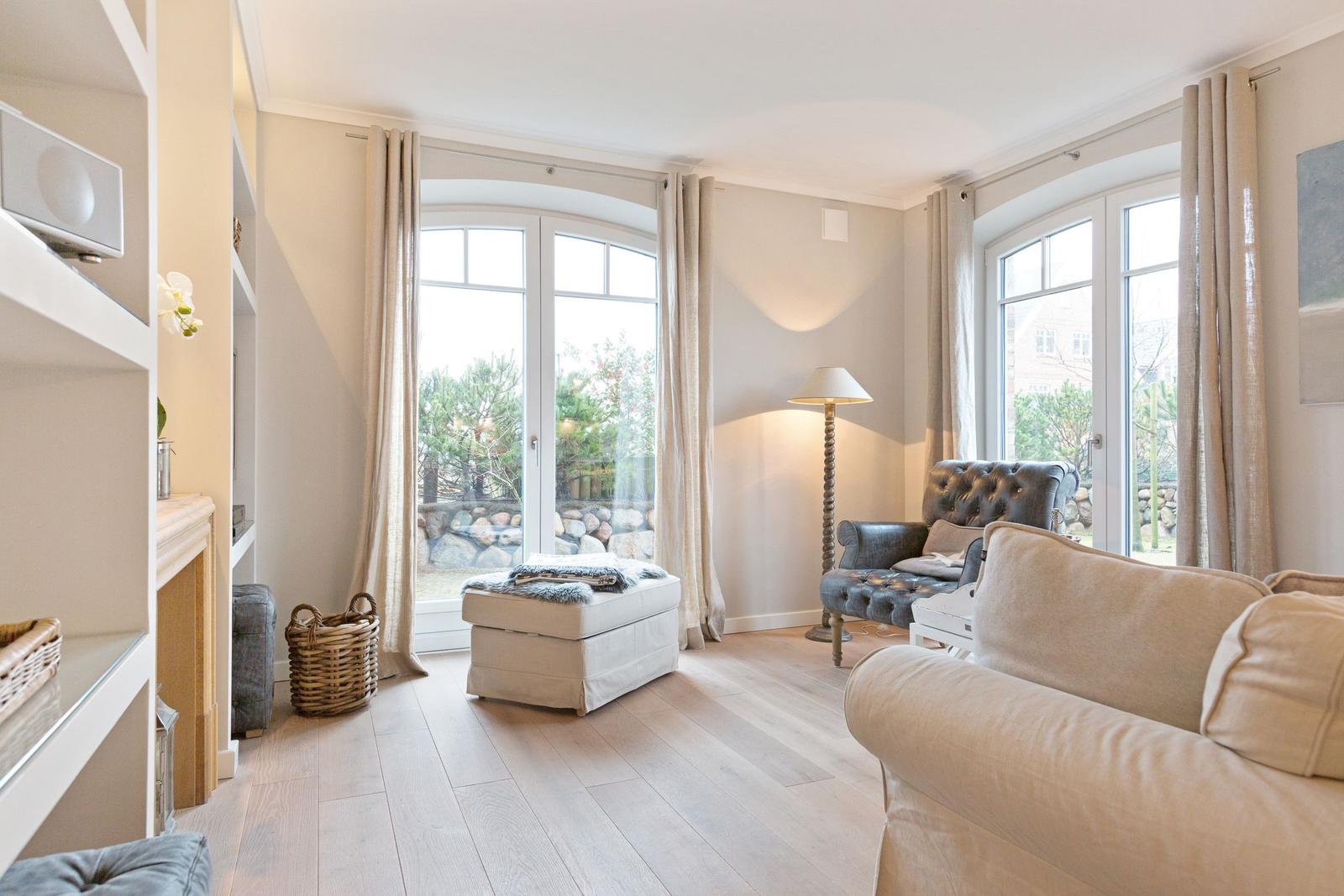 Wohnzimmer mit Sofa, Sessel und großem Fenster zum Garten.