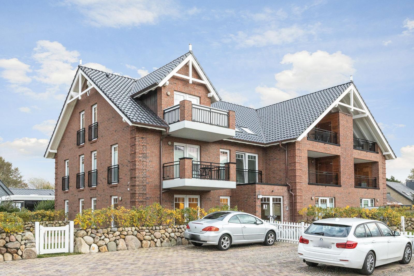 Two-story house with balconies and paved driveway.