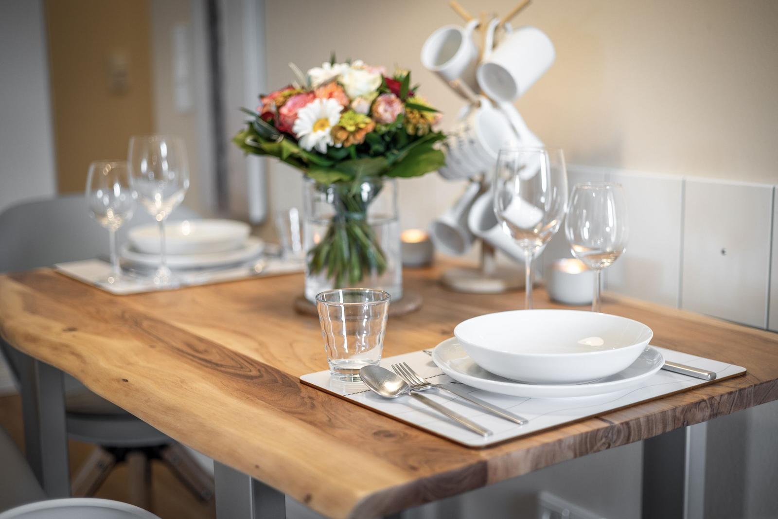 Dining table with plates, glasses, and flower arrangement.