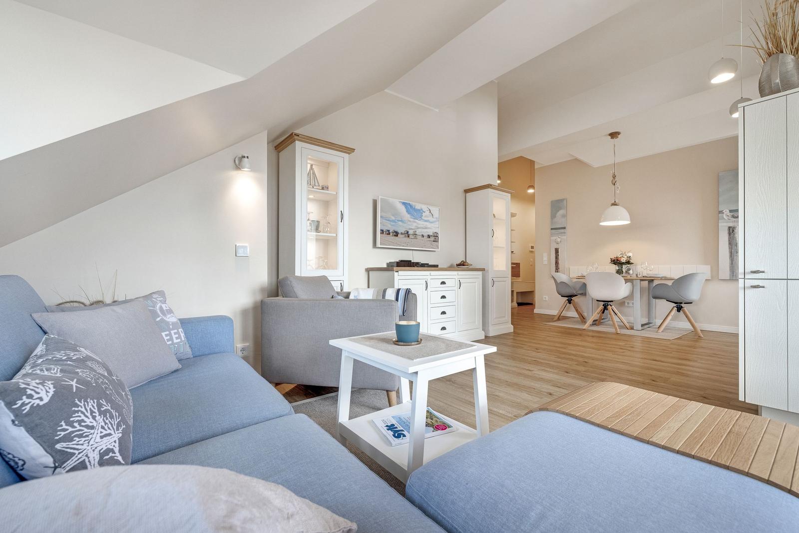 Living and dining area with sofa, table, and chairs. Wooden floor and white furniture.