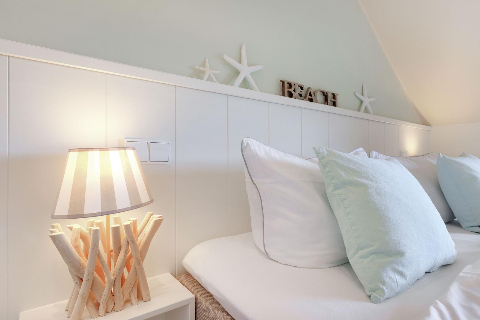 Bedroom with bed, pillows, and nightstand with lamp.