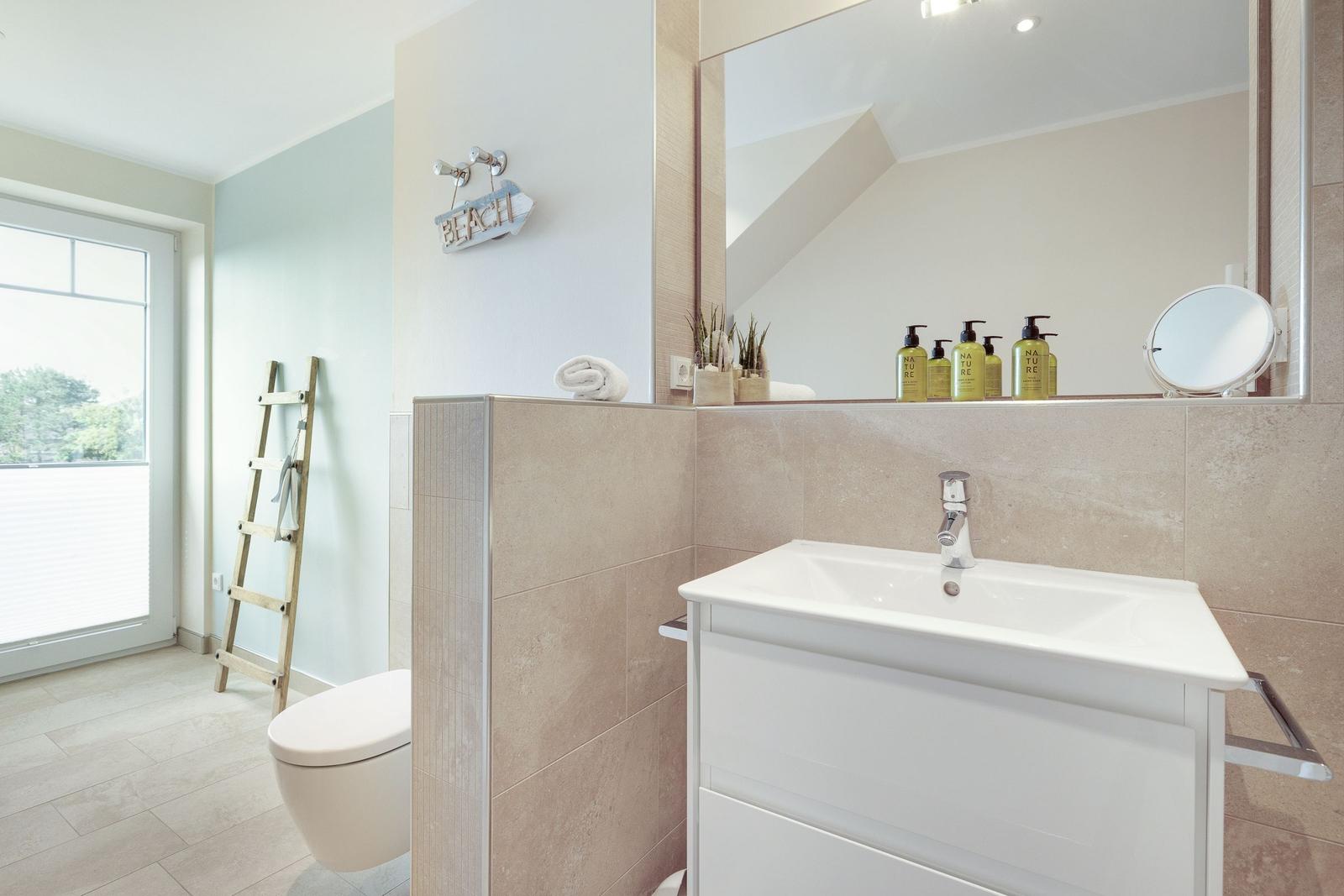 Bathroom with sink, mirror, toilet, and window