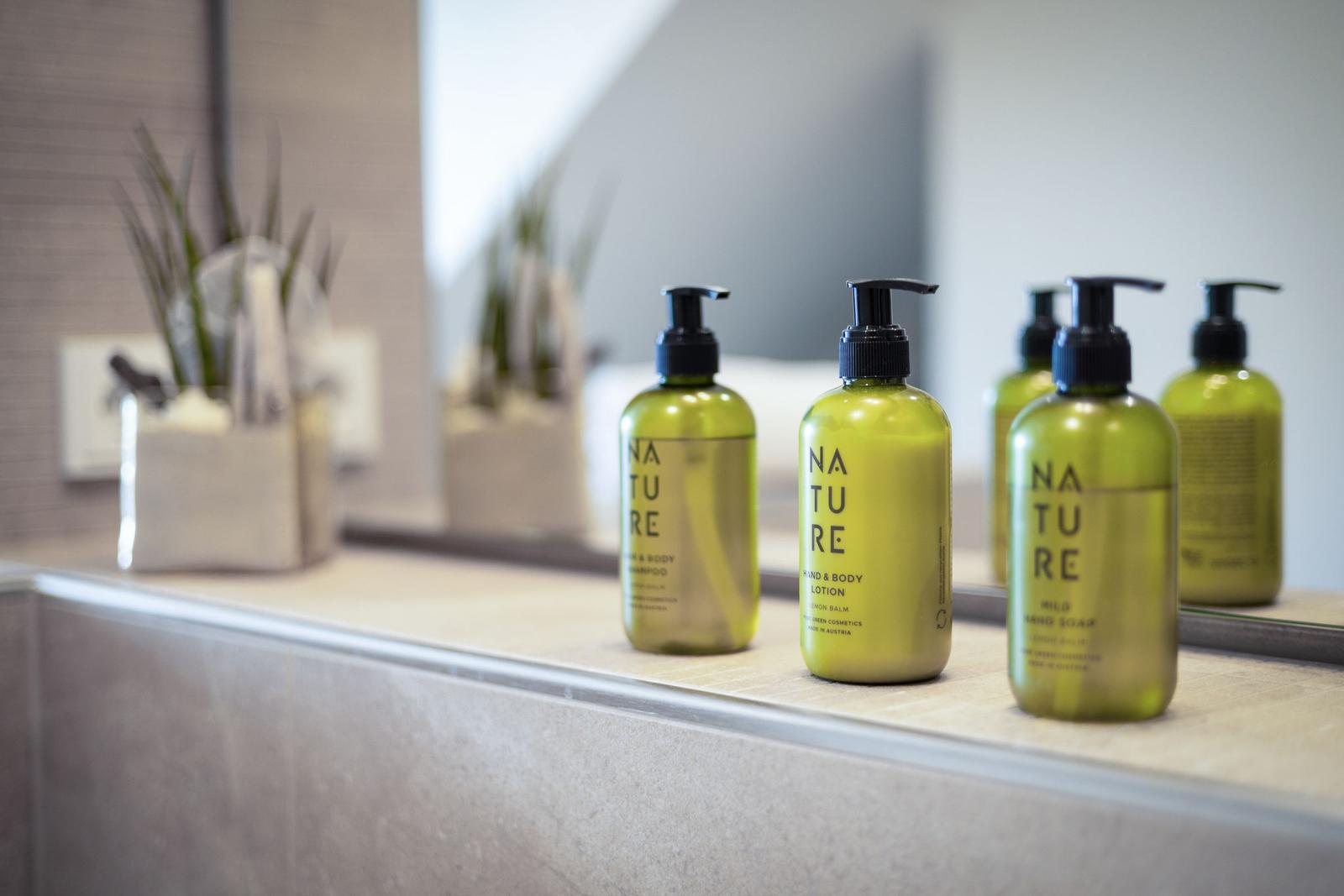 Bathroom with green Nature soap bottles and plant on sink