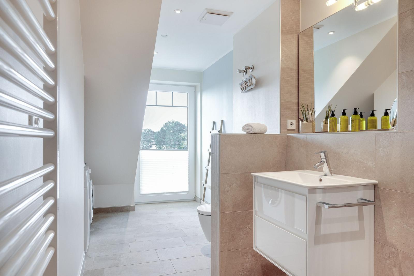 Bathroom with sink, mirror, shower, and window.