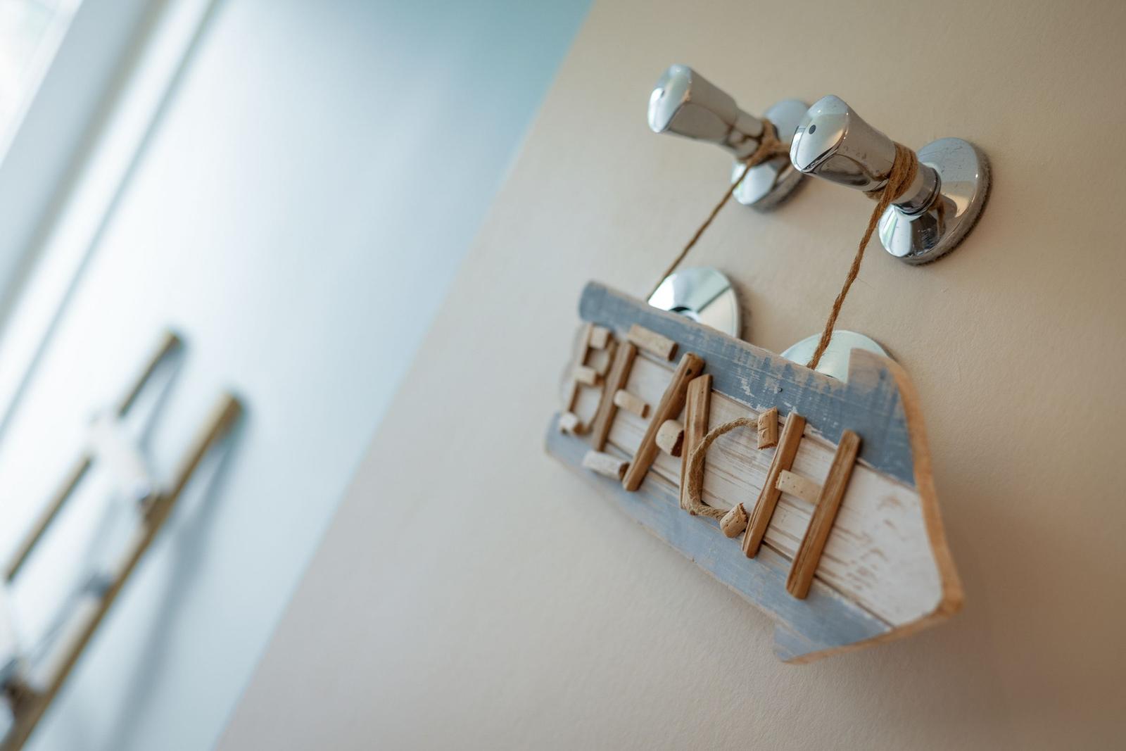Wooden sign with the word Beach hangs on chrome hooks on the wall.