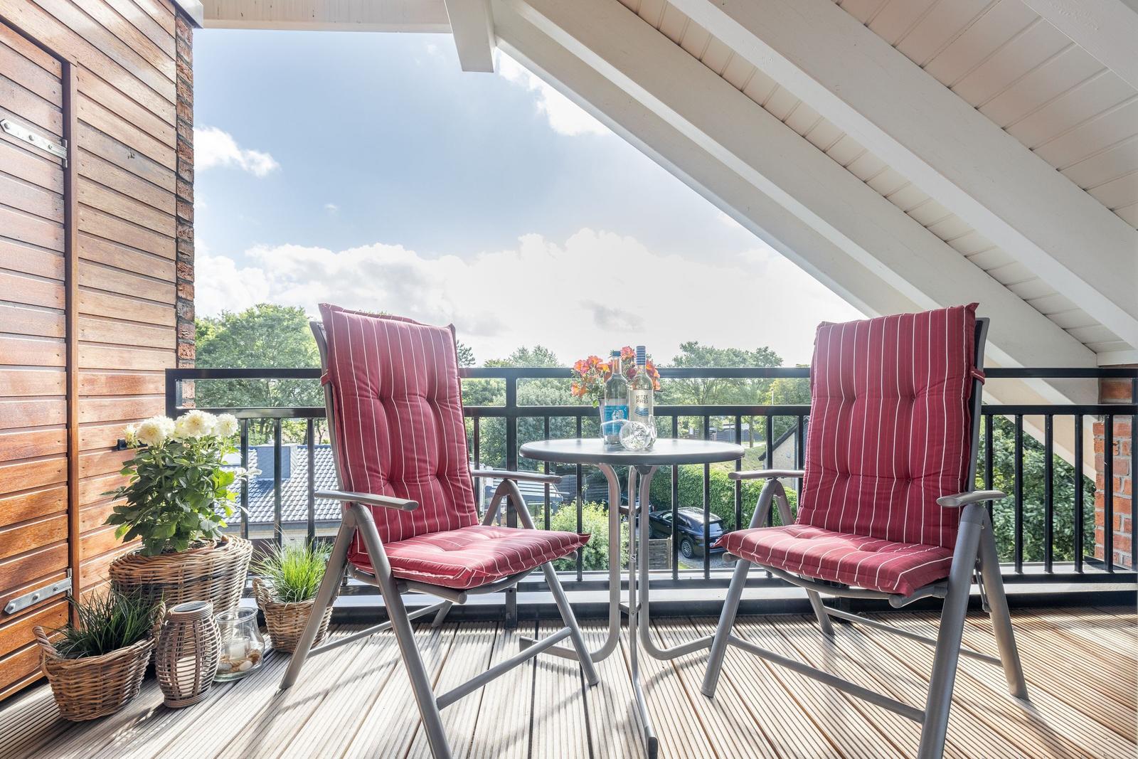 Terrace with two chairs, table, and plants. View of green surroundings.