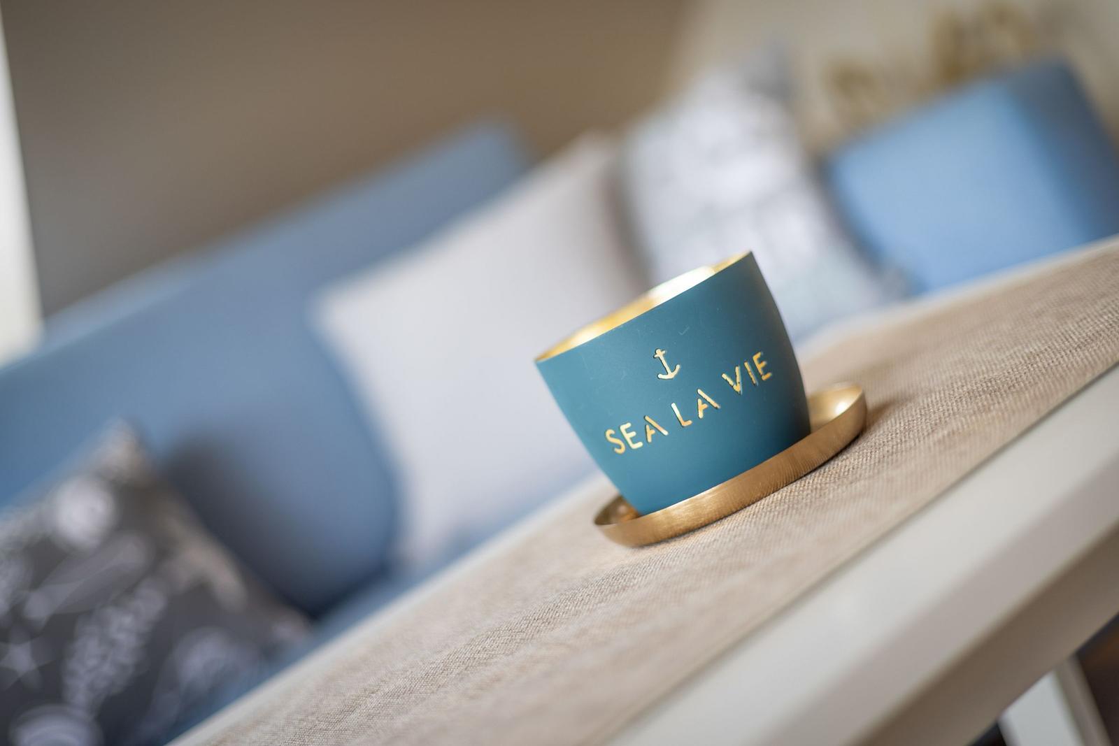 A blue cup with gold lettering sits on a table.