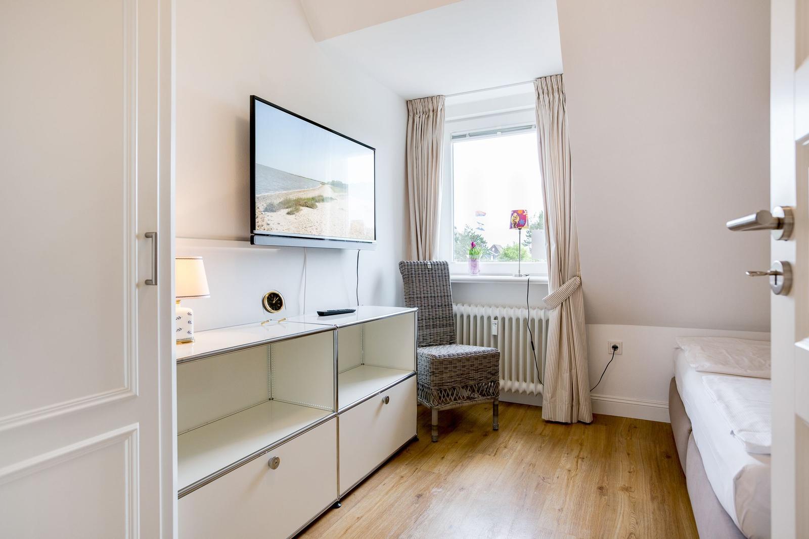 Schlafzimmer mit TV, Stuhl und Fenster
