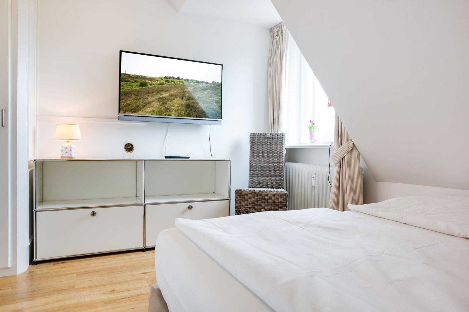 Schlafzimmer mit Bett, Fernseher und Fenster