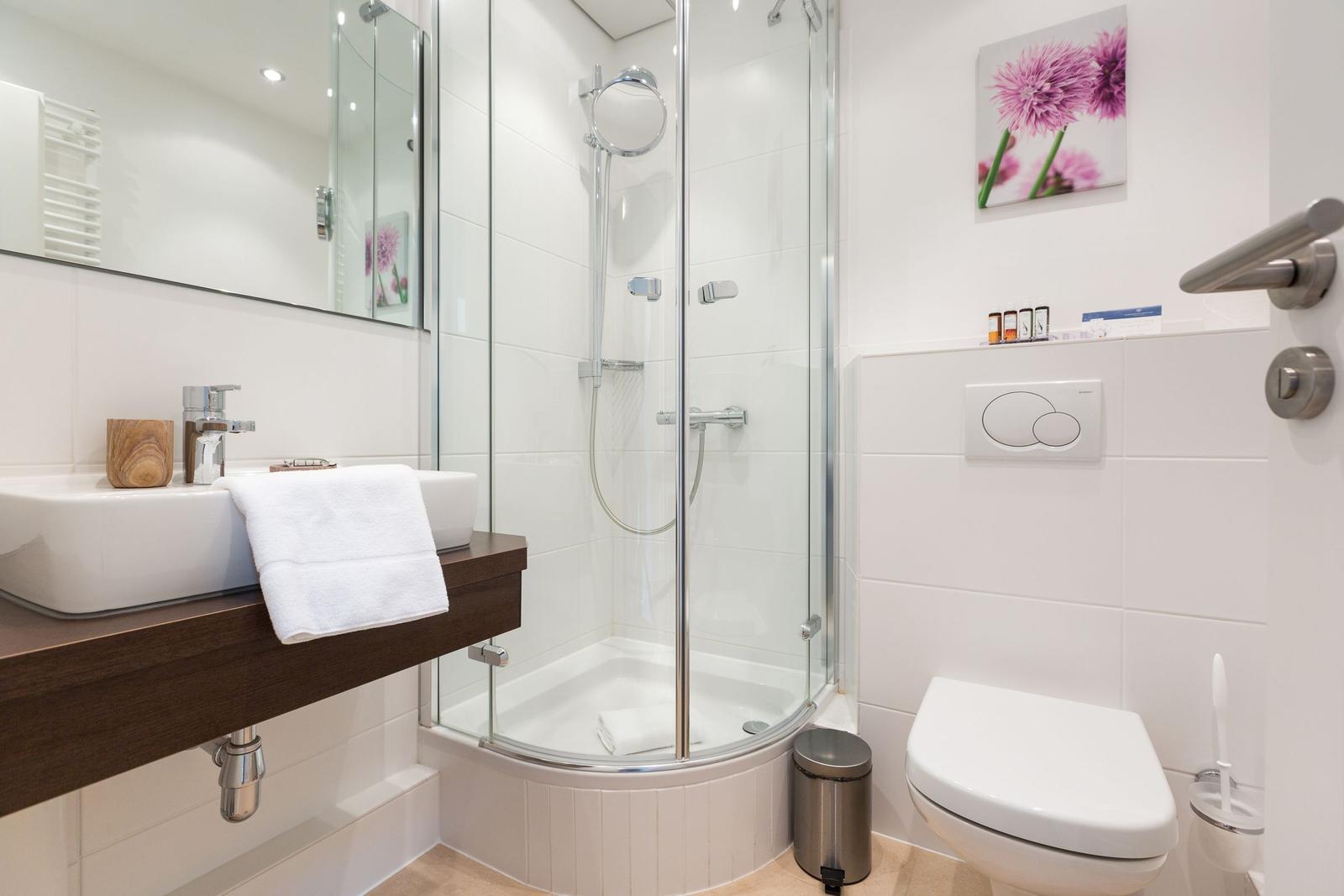 Badezimmer mit Dusche, Waschbecken und Toilette.