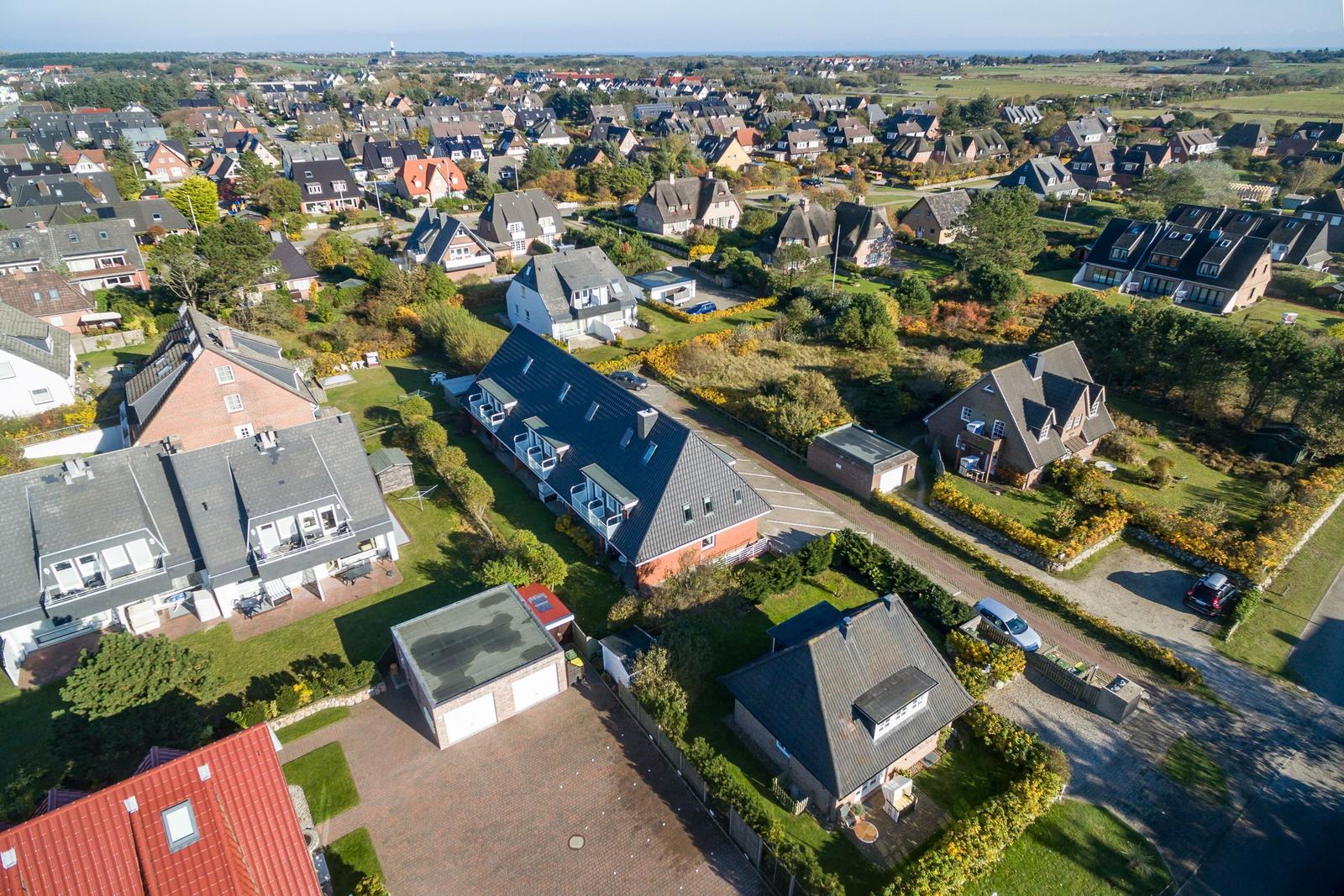 Luftbild einer Wohngegend mit mehreren Häusern und grünen Gärten.